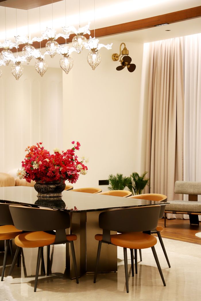Stylish dining room interior featuring a modern chandelier, large table, and vibrant floral centerpiece.